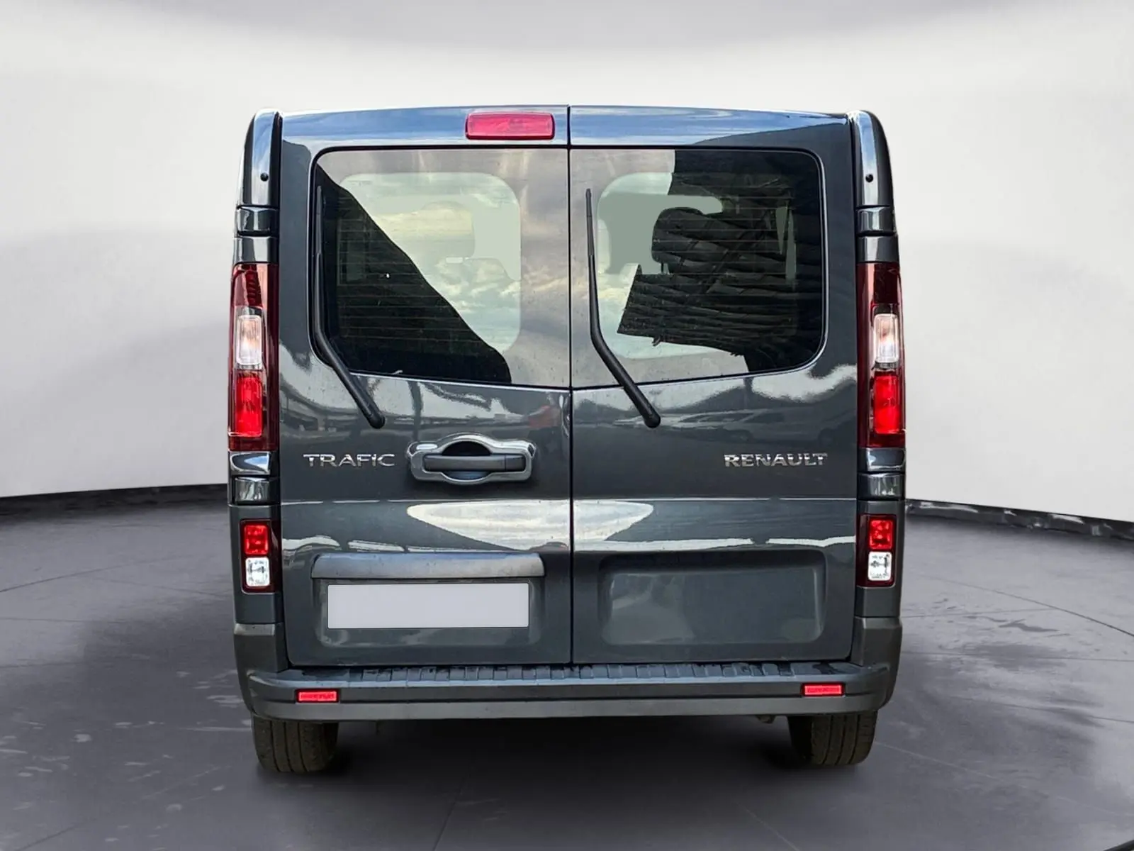 Vue arrière du Renault Trafic Combi gris foncé métallisé avec portes vitrées et essuie-glaces arrière visibles.