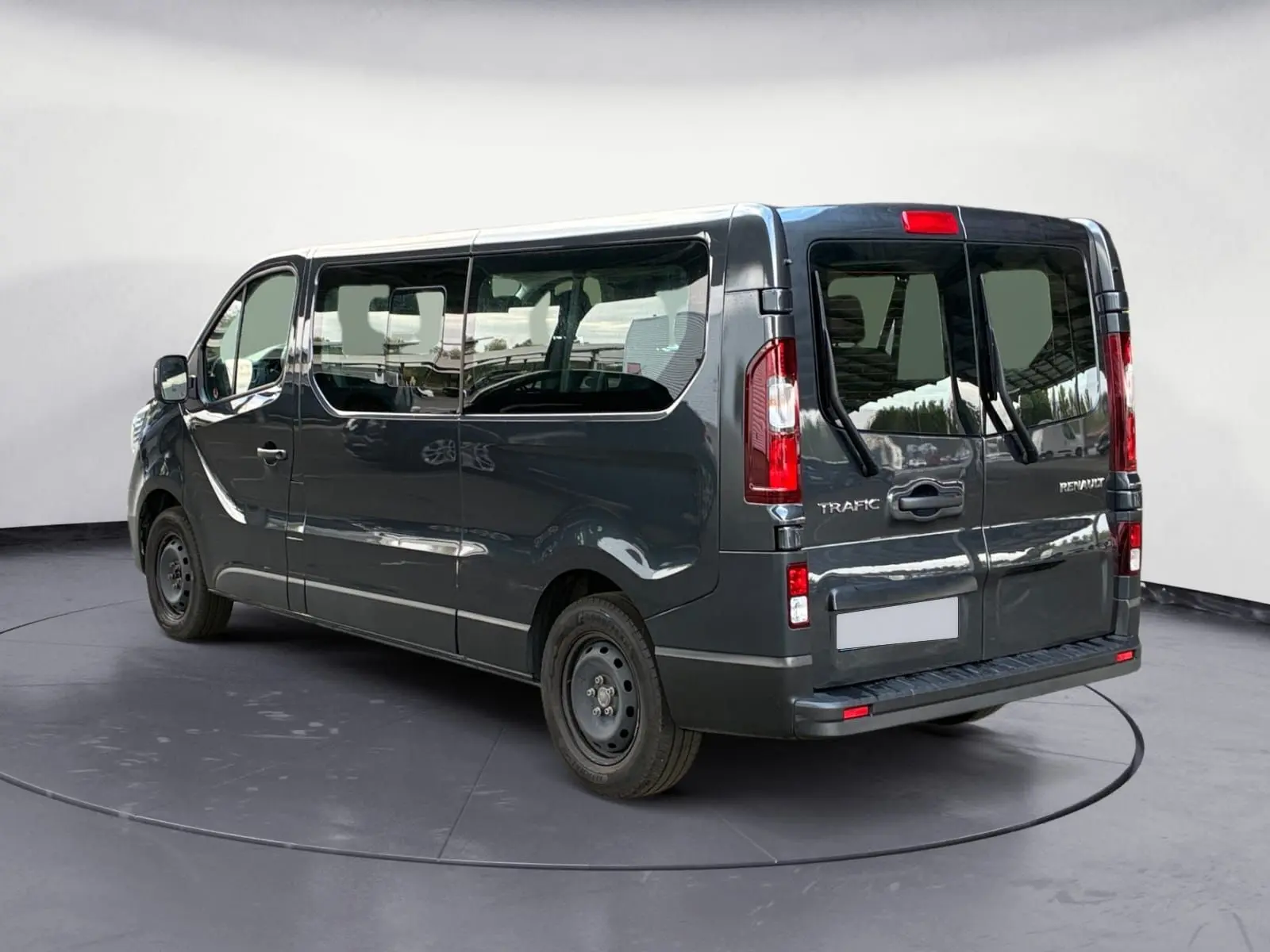 Vue 3/4 arrière droite d'un Renault Trafic Combi gris foncé métallisé avec vitres latérales teintées et hayon double.