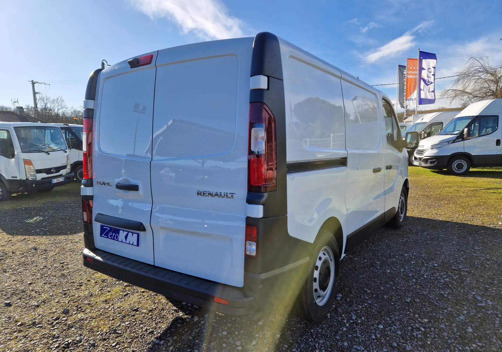 Vue 3/4 arrière droite d’un Renault Trafic Fourgon blanc 2025, avec portes arrière fermées et jantes acier.