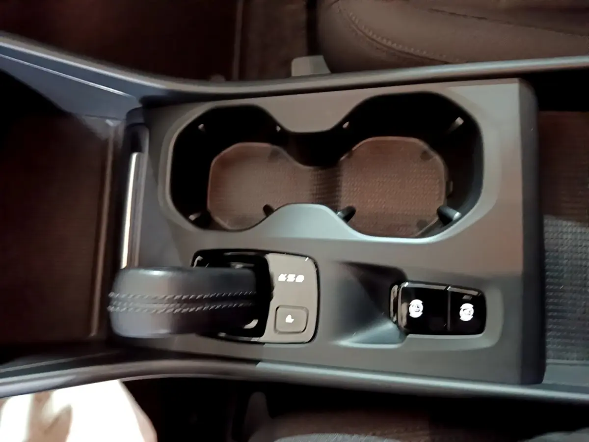 Gros plan sur la console centrale noire du Volvo XC40 Recharge T4 avec levier de vitesse et boutons de contrôle.