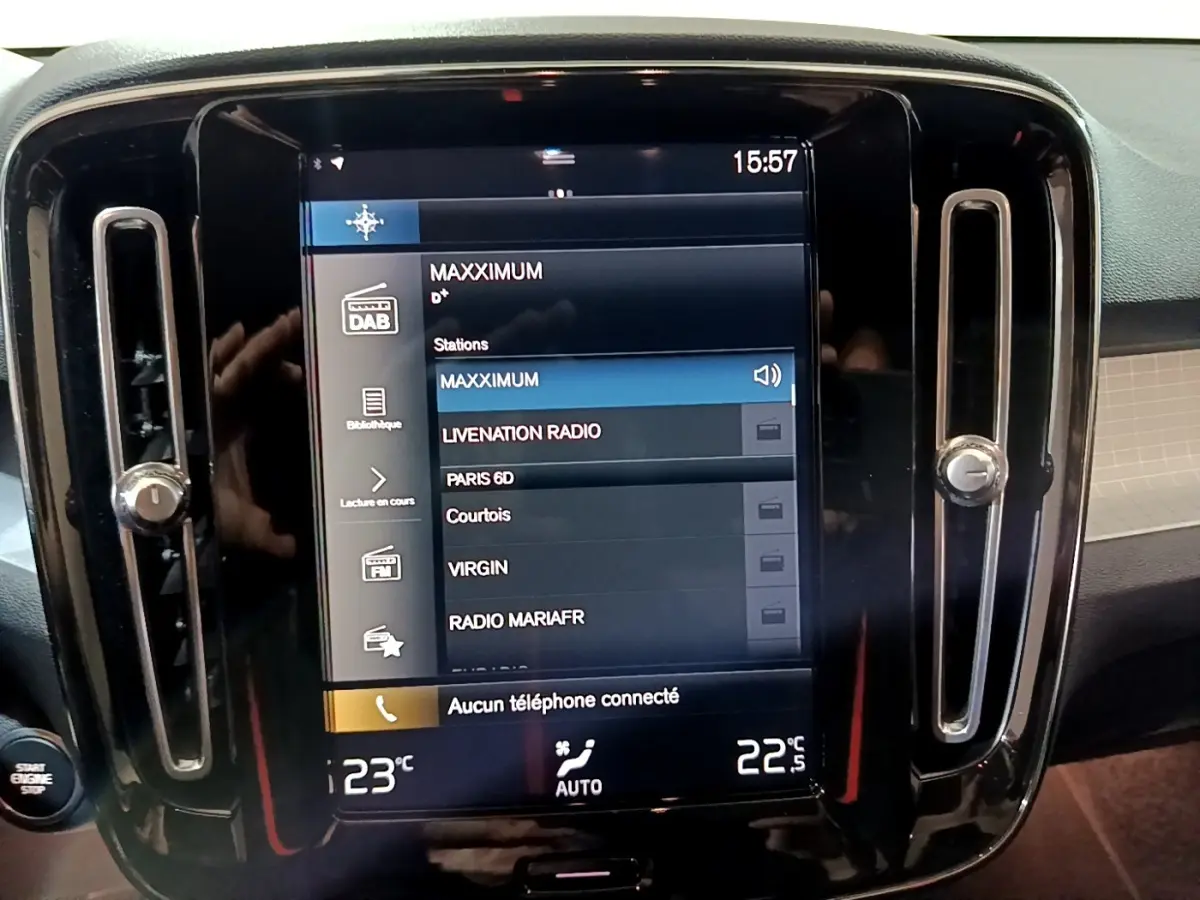 Écran tactile central allumé affichant stations radio, entouré de sorties d'air verticales noires dans Volvo XC40 noir.