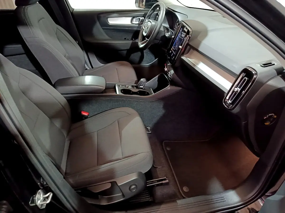 Vue intérieure côté passager du Volvo XC40 Recharge T4 Business 2020, sièges tissu gris et tableau de bord moderne noir et argent.