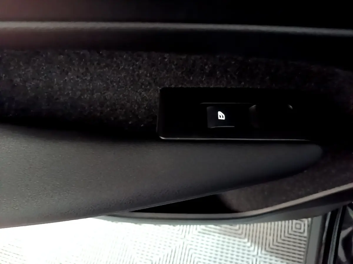 Gros plan sur le bouton de commande de la vitre côté conducteur d'un Volvo XC40 noir, intérieur sombre.