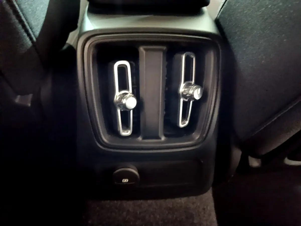Gros plan sur les commandes d'aération arrière noires du Volvo XC40 Recharge T4 Business 2020, intérieur sombre.
