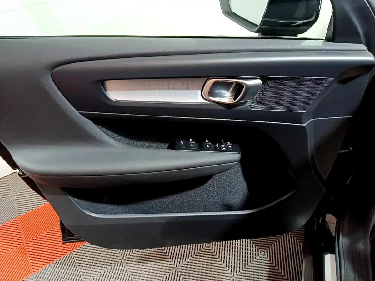 Gros plan sur la porte côté gauche du Volvo XC40 noir, avec poignée alu et commandes électriques des vitres.