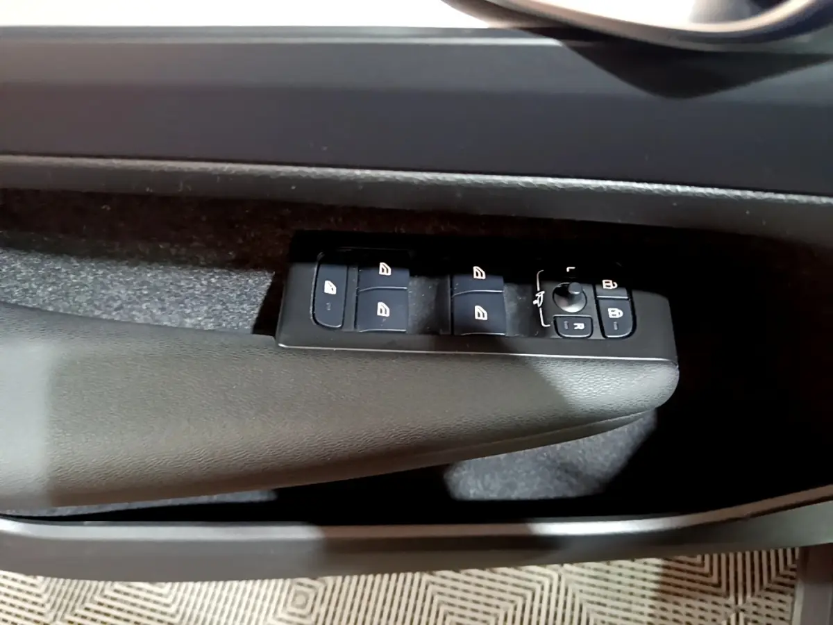 Gros plan sur les commandes des vitres électriques côté conducteur du Volvo XC40 Recharge T4 noir, intérieur sombre.