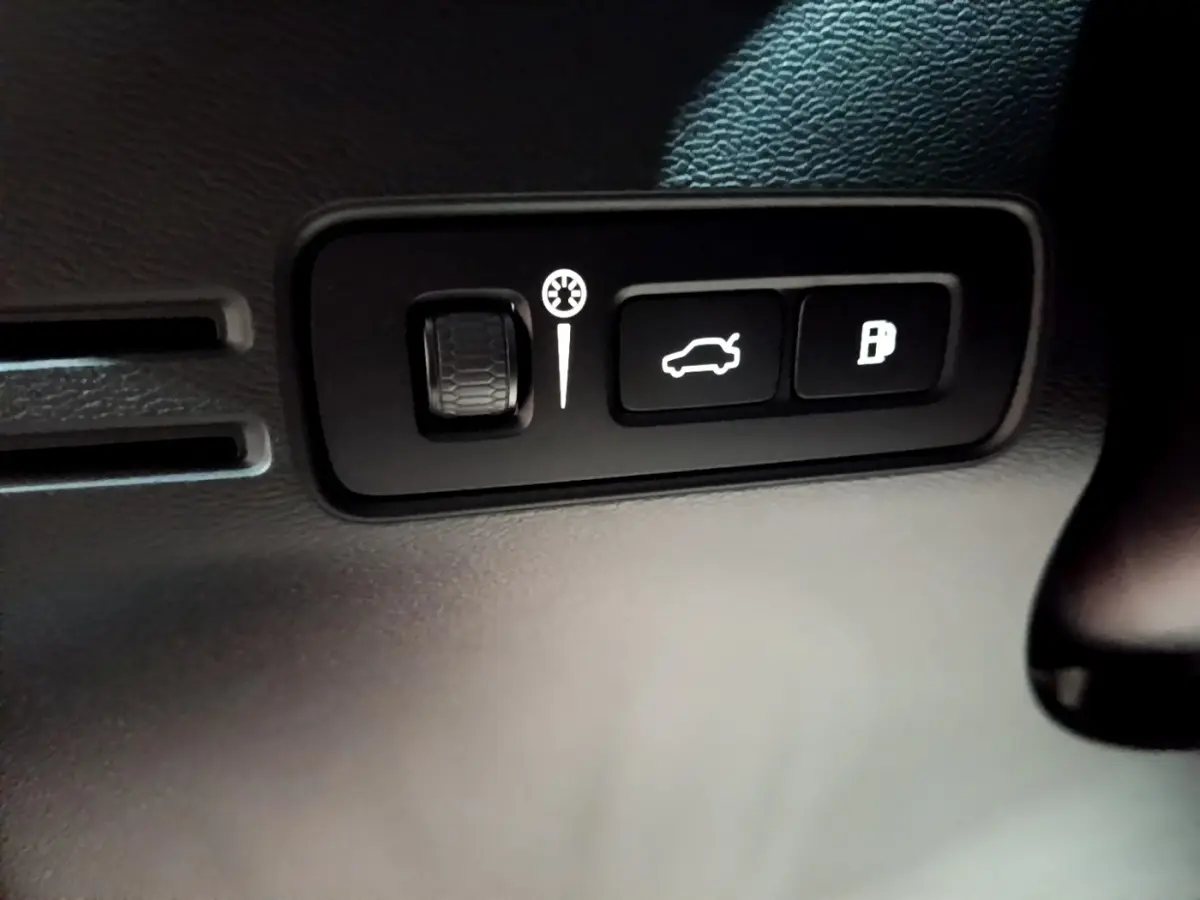 Gros plan sur les commandes d'ouverture du coffre et du réservoir dans l'habitacle noir du Volvo XC40 Recharge T4 Business.