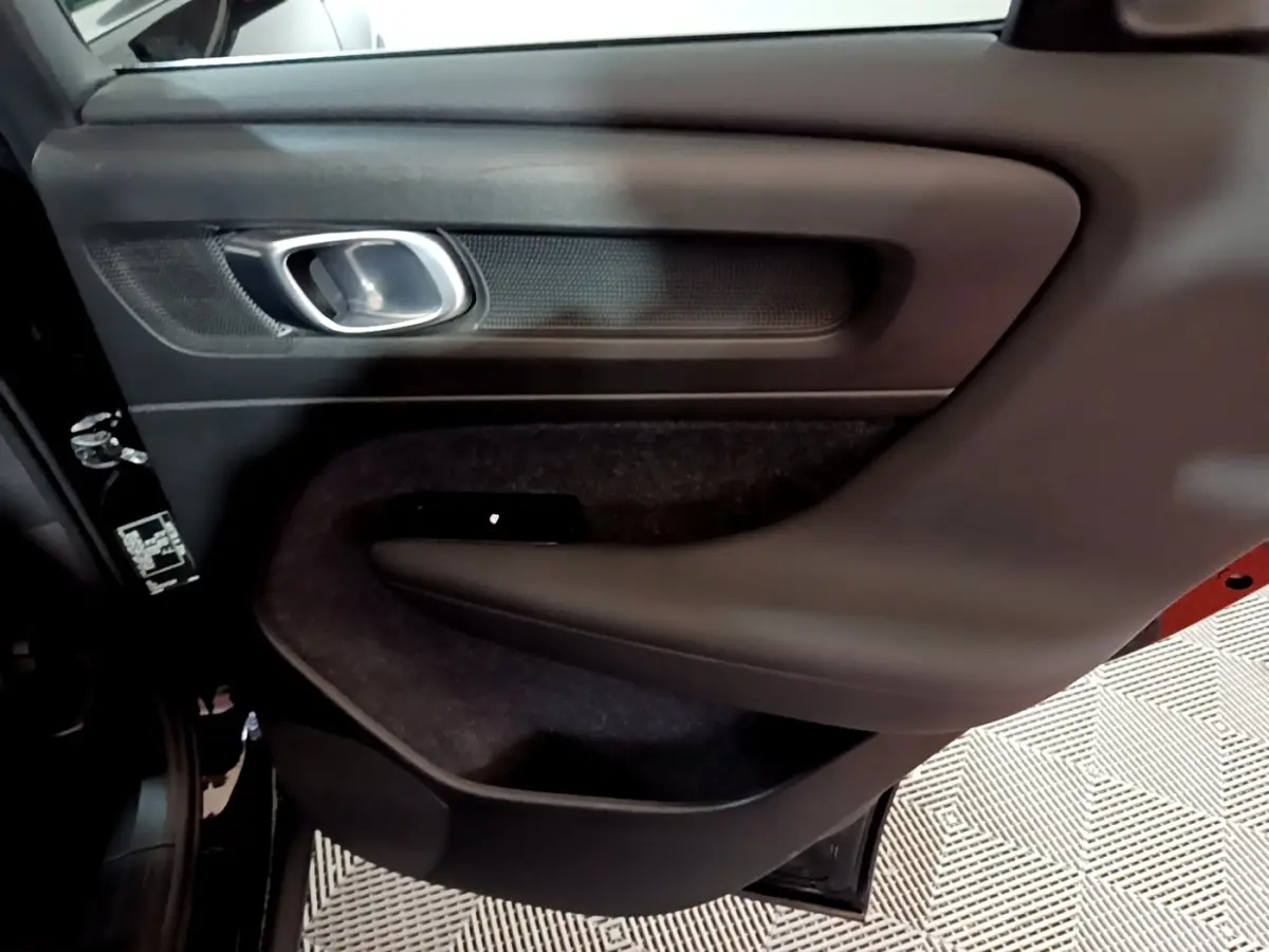 Gros plan sur la porte arrière gauche noire du Volvo XC40 Recharge T4, avec poignée argentée et garniture noire.