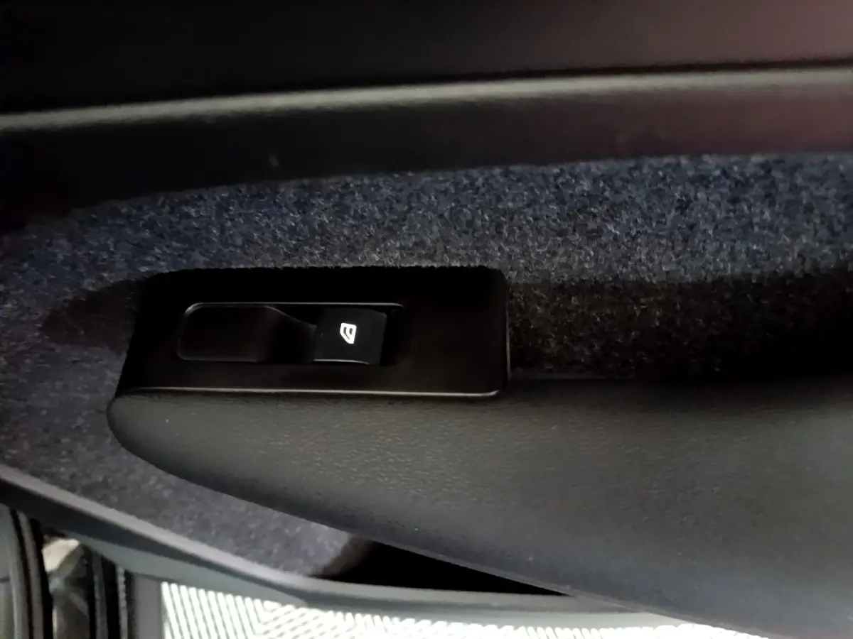 Gros plan sur le bouton de lève-vitre noir intégré à la garniture intérieure côté conducteur d'un Volvo XC40 noir.
