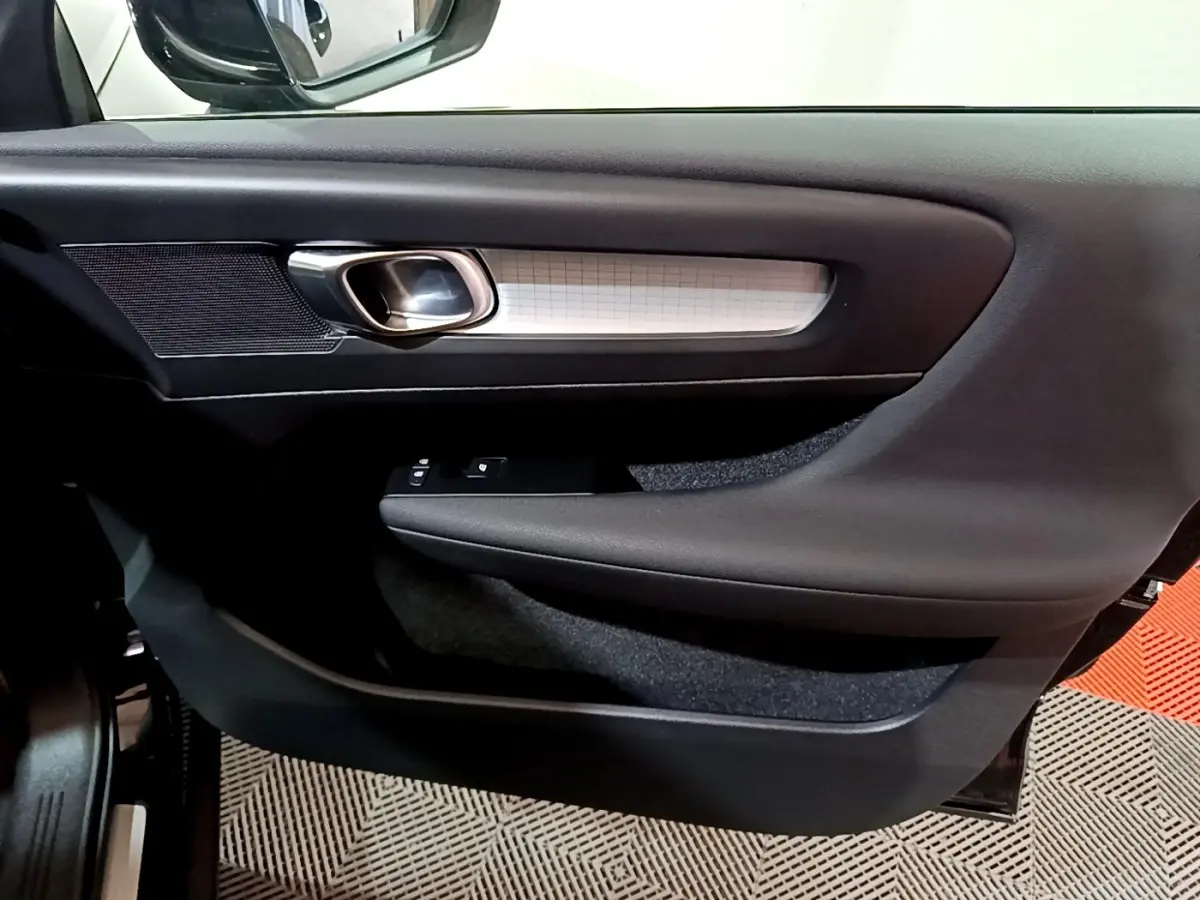 Détail de la porte côté conducteur du Volvo XC40 noir, avec poignée argentée et commandes de vitres intégrées.