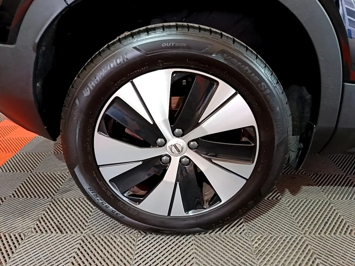 Gros plan sur la roue avant droite du Volvo XC40 noir, mettant en valeur la jante bicolore et le pneu Hankook.
