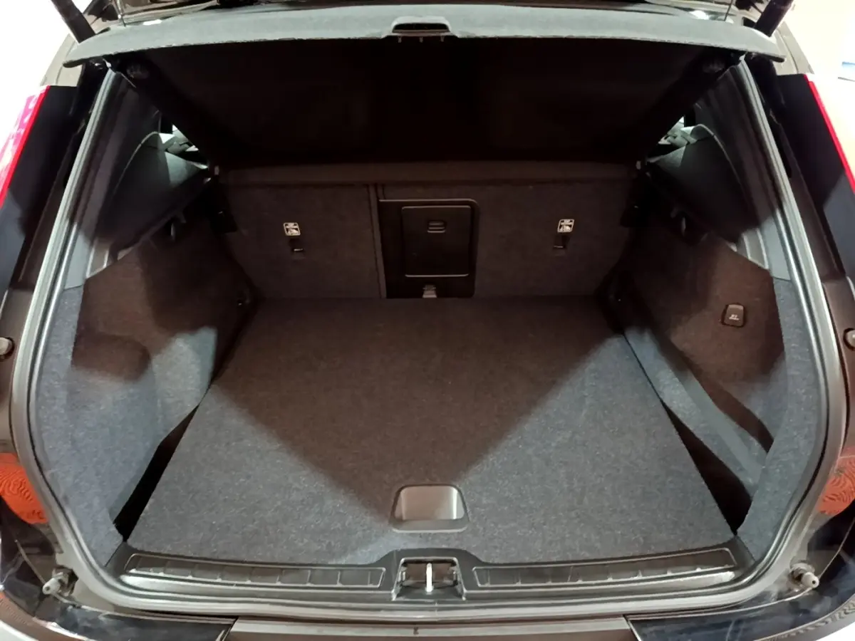 Coffre ouvert d'un Volvo XC40 noir, vue intérieure arrière montrant l'espace de chargement et revêtement gris.