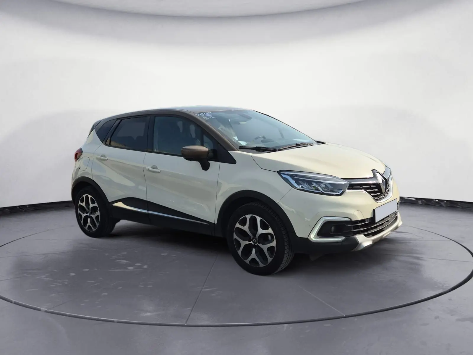 Renault Captur beige/marron vue 3/4 avant droit, avec jantes alliage et détails noirs contrastants.