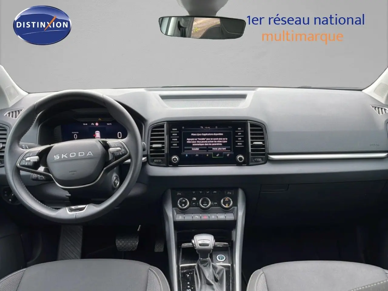 Vue intérieure avant du Skoda Karoq blanc glacier 2025, tableau de bord moderne avec écran tactile et volant cuir multifonction.