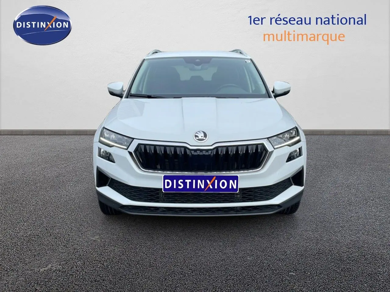 Vue frontale d'un Skoda Karoq blanc glacier 2025 avec calandre noire et phares LED distinctifs.