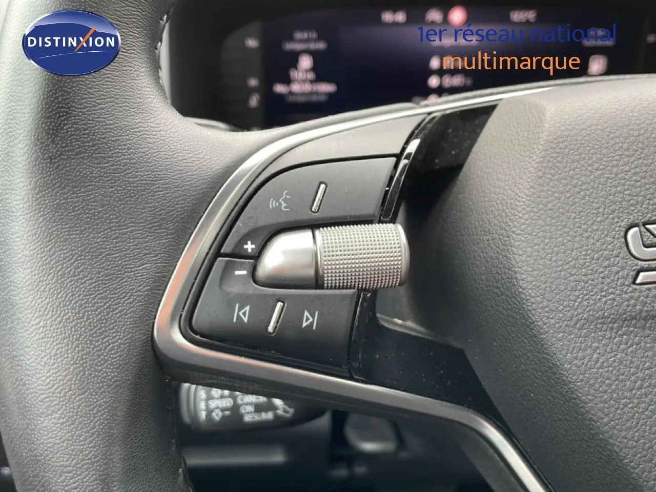 Gros plan sur les commandes au volant du Skoda Karoq blanc glacier 2025, mettant en valeur la molette et les boutons multifonctions.