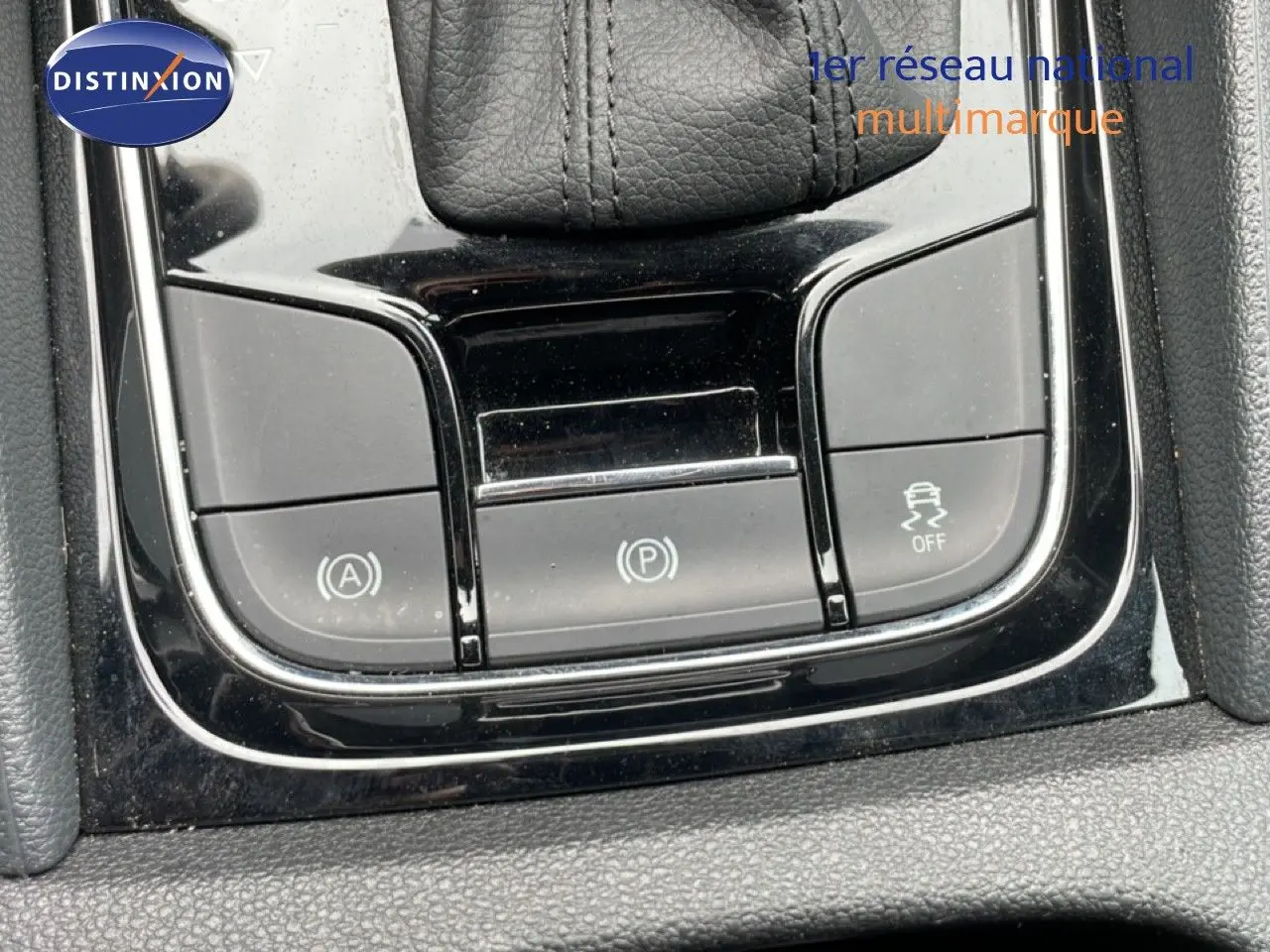Gros plan sur les commandes de la console centrale noire du Skoda Karoq blanc glacier, mettant en valeur les boutons de frein à main et d'assistance.
