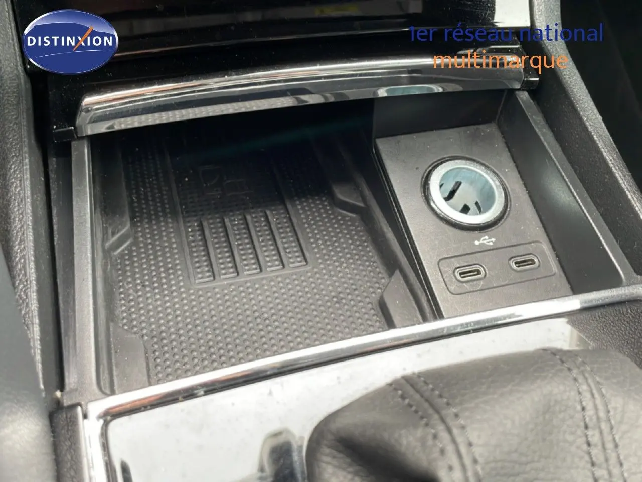 Gros plan sur la console centrale noire du Skoda Karoq blanc glacier, avec prise USB et allume-cigare visible.