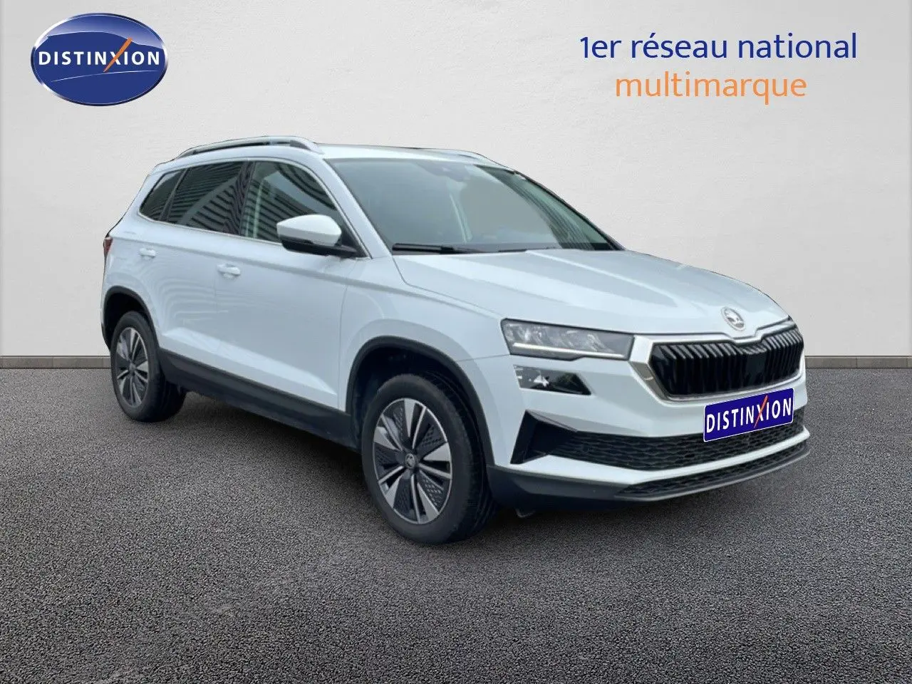 Vue 3/4 avant gauche d'un Skoda Karoq blanc glacier avec calandre noire et jantes bi-ton.