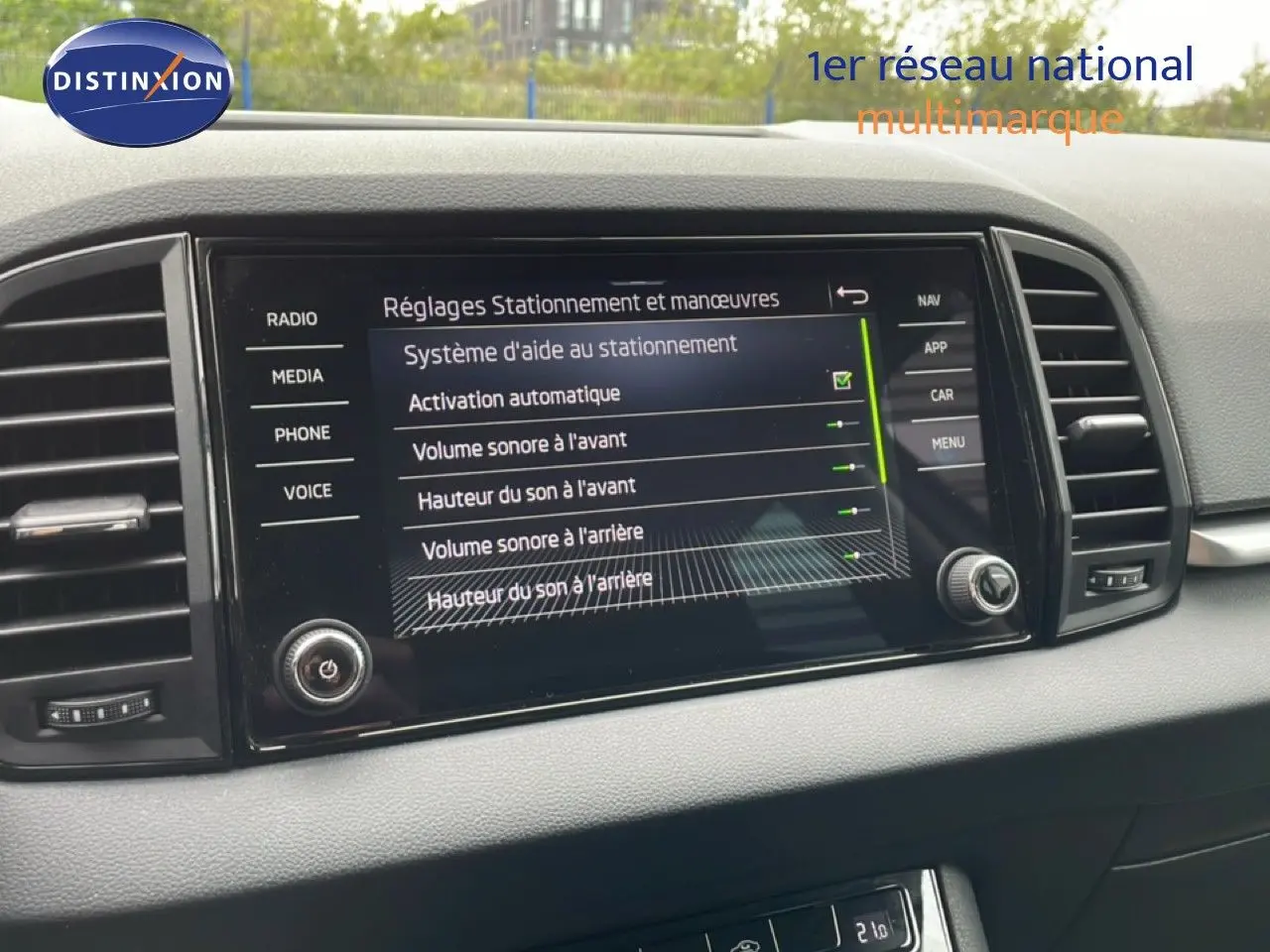 Vue rapprochée de l’écran central tactile du Skoda Karoq blanc glacier 2025 affichant les réglages d’aide au stationnement.