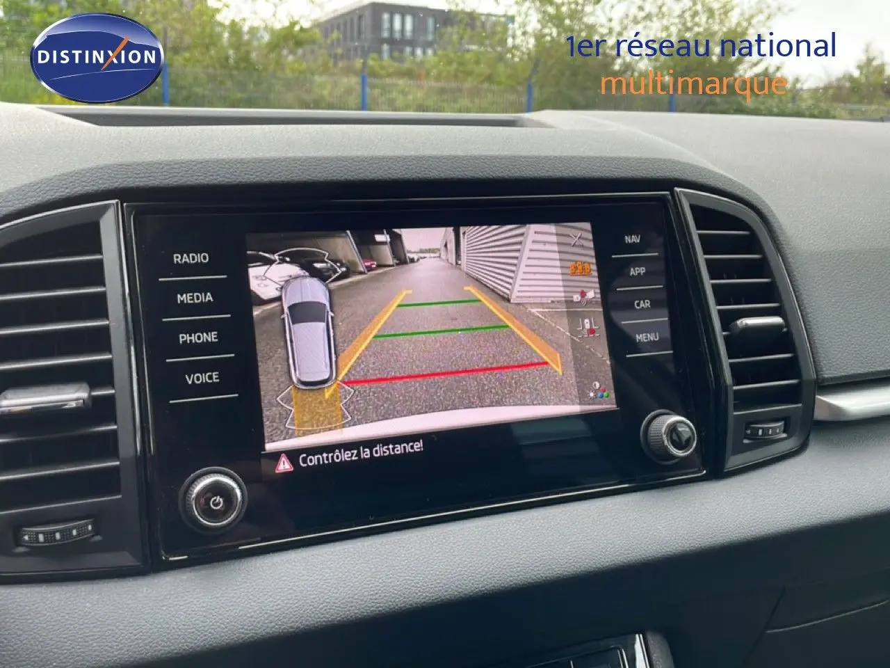 Écran central de la Skoda Karoq blanc glacier montrant la caméra de recul avec guidage de trajectoire coloré.