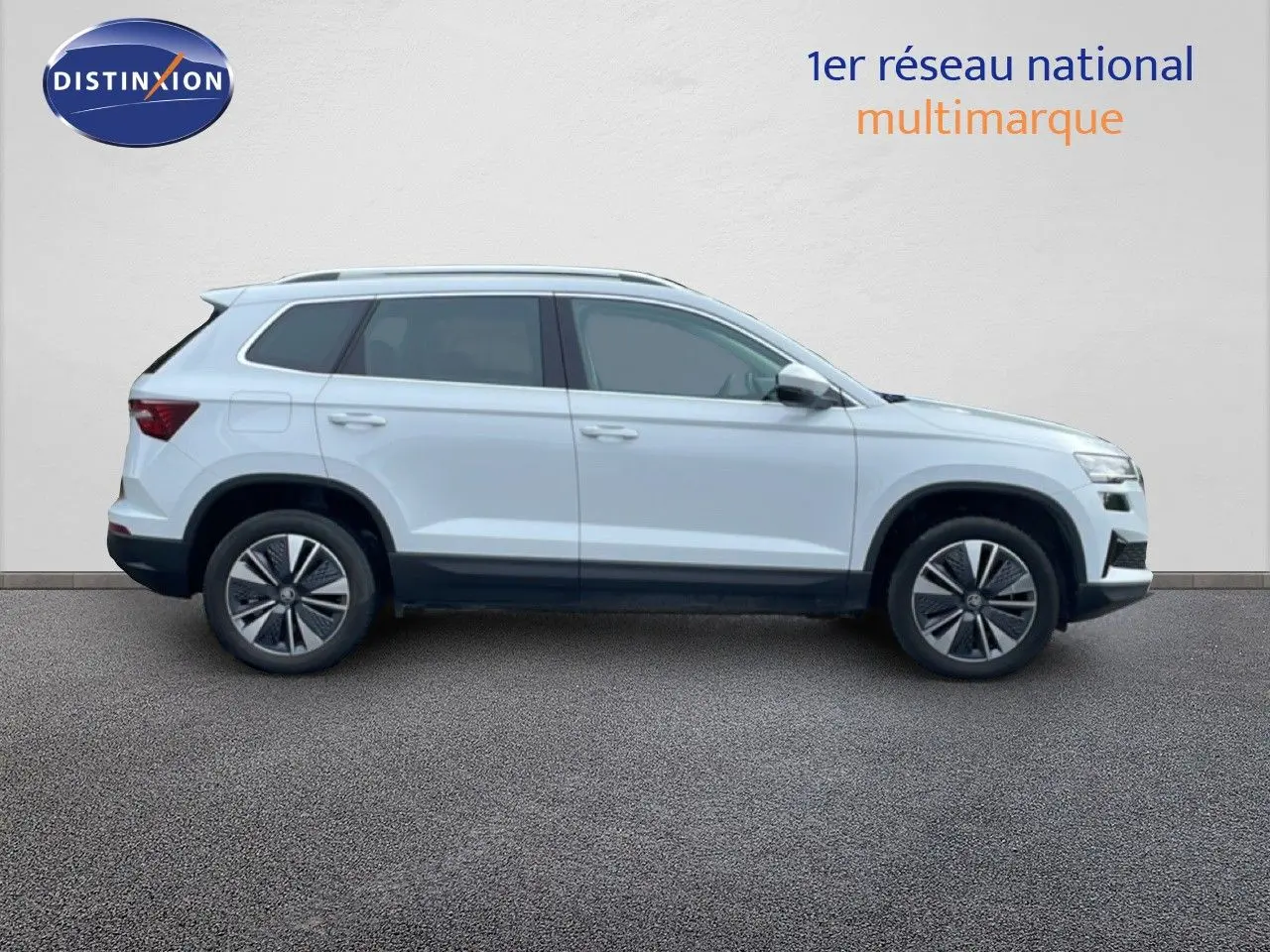 Vue de profil côté gauche d'un Skoda Karoq blanc glacier 2025 avec jantes bi-ton et toit ouvrant.