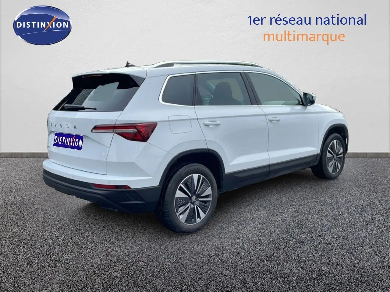 SKODA KAROQ blanc glacier vu en 3/4 arrière droit, avec jantes bi-ton et vitres teintées.