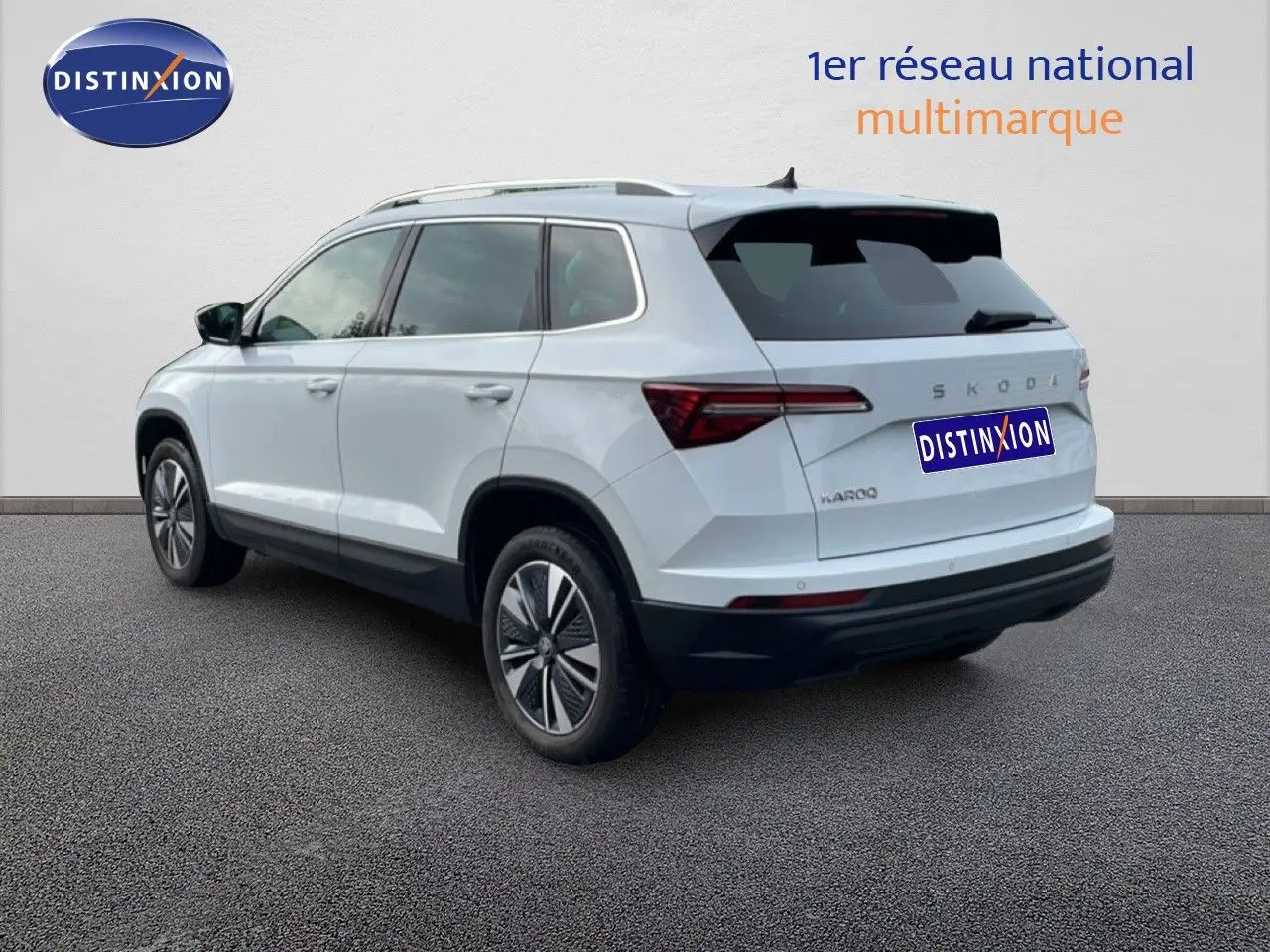 Vue 3/4 arrière droite d'un Skoda Karoq blanc glacier avec jantes bi-ton et vitres teintées.