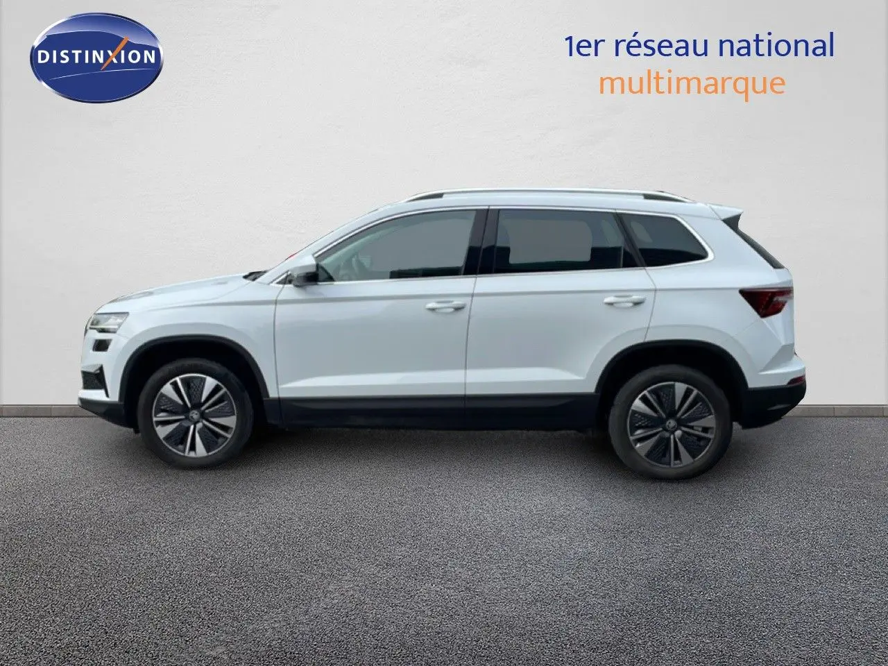 Vue de profil côté gauche d'un Skoda Karoq blanc glacier 2025 avec jantes bi-ton et toit surélevé.