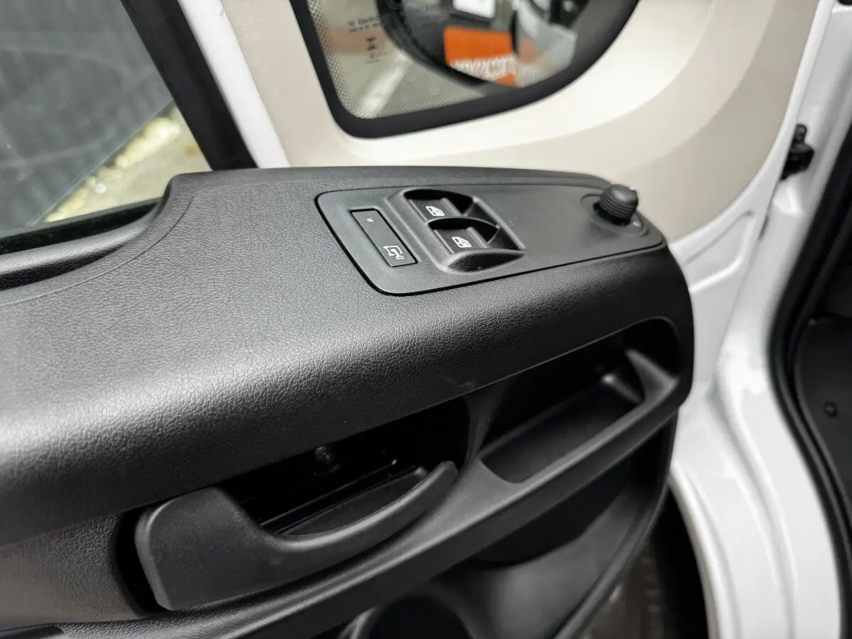 Détail de la porte avant gauche blanche du Peugeot Boxer Fourgon avec commandes électriques des vitres et rétroviseur.