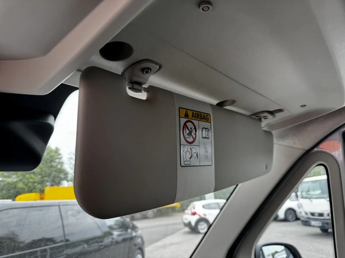 Pare-soleil gris clair côté conducteur du Peugeot Boxer Fourgon blanc, vue intérieure avec autocollant airbag visible.