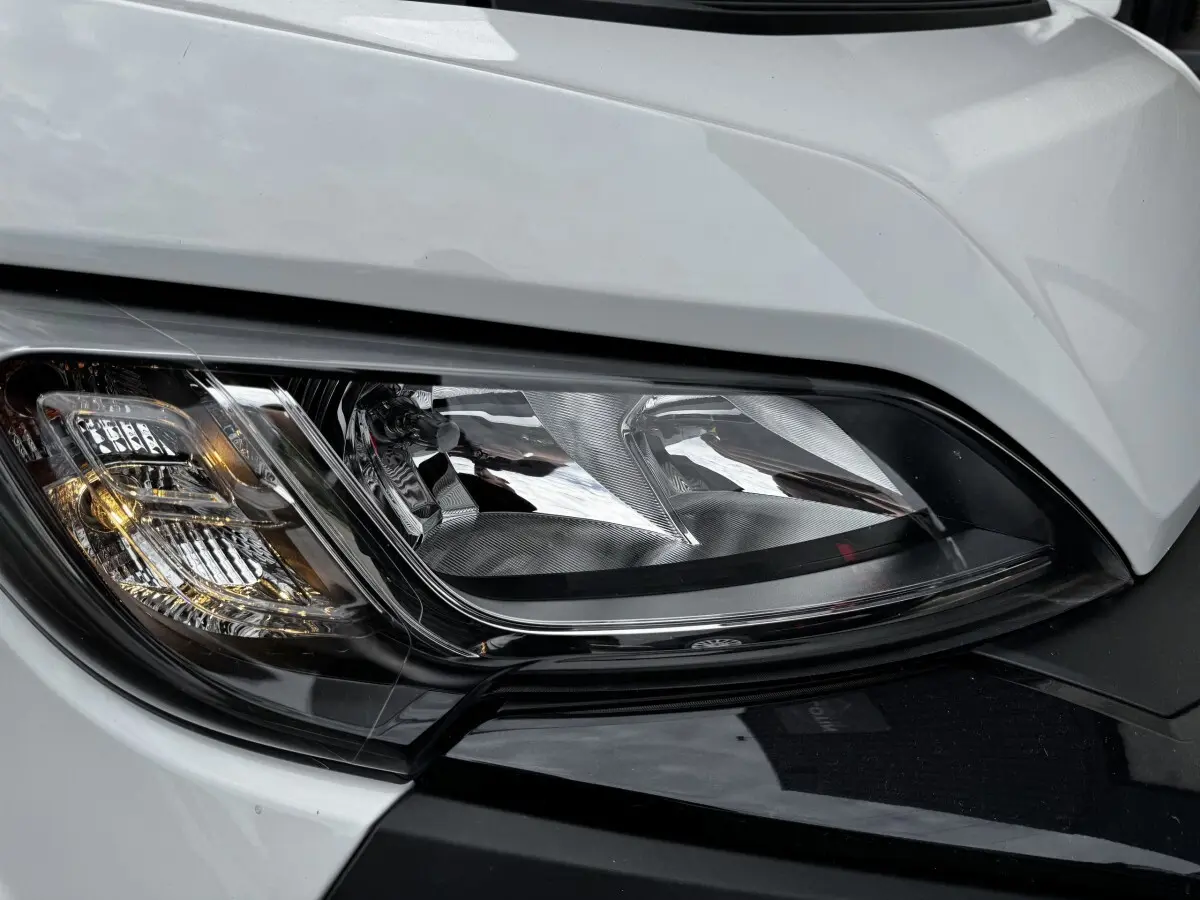 Gros plan sur le phare avant droit du Peugeot Boxer Fourgon blanc, mettant en valeur ses détails lumineux et contours noirs.