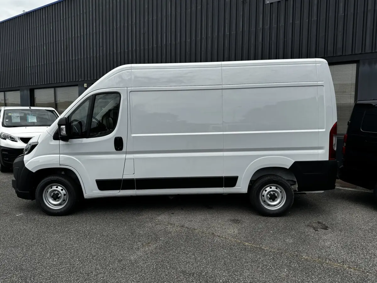 Vue de profil côté gauche d'un Peugeot Boxer Fourgon blanc, avec protections noires sur les bas de caisse et roues acier.