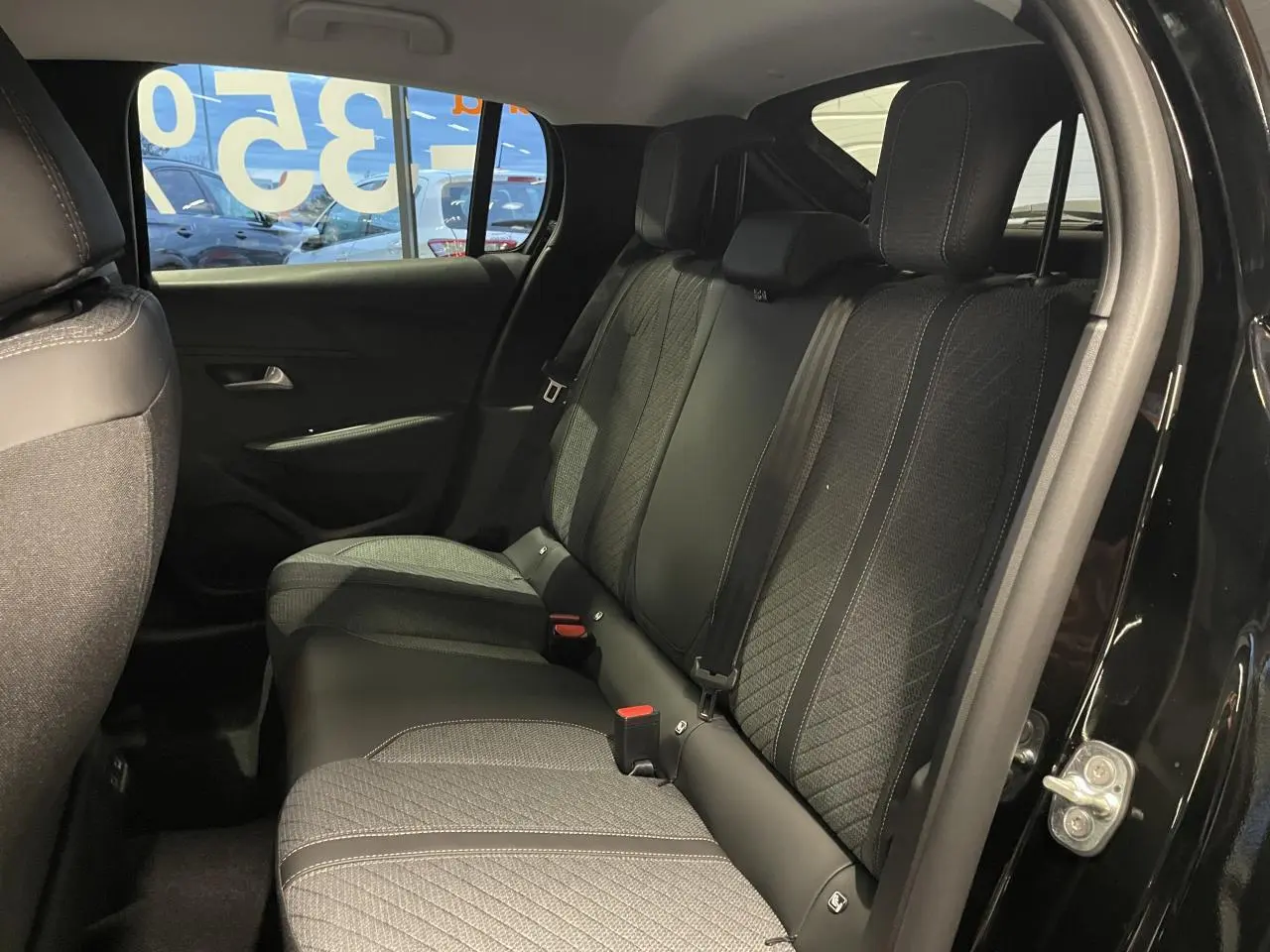 Vue intérieure côté droit sur la banquette arrière tissu noir et gris d’une Peugeot 208 noire métallisée 2025.