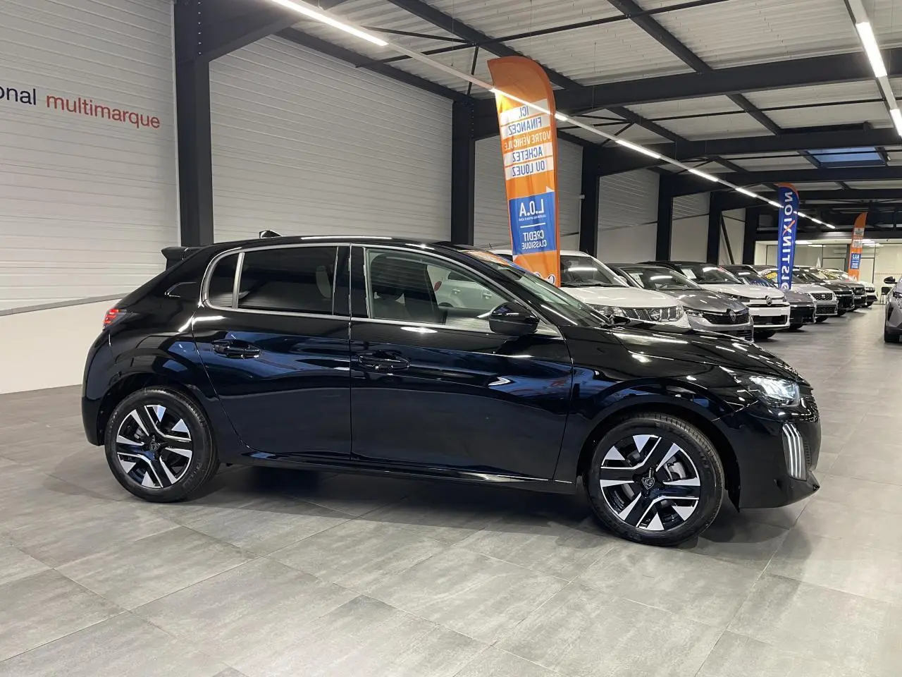 Peugeot 208 hybride noir métallisé vue de profil côté gauche en intérieur de showroom.