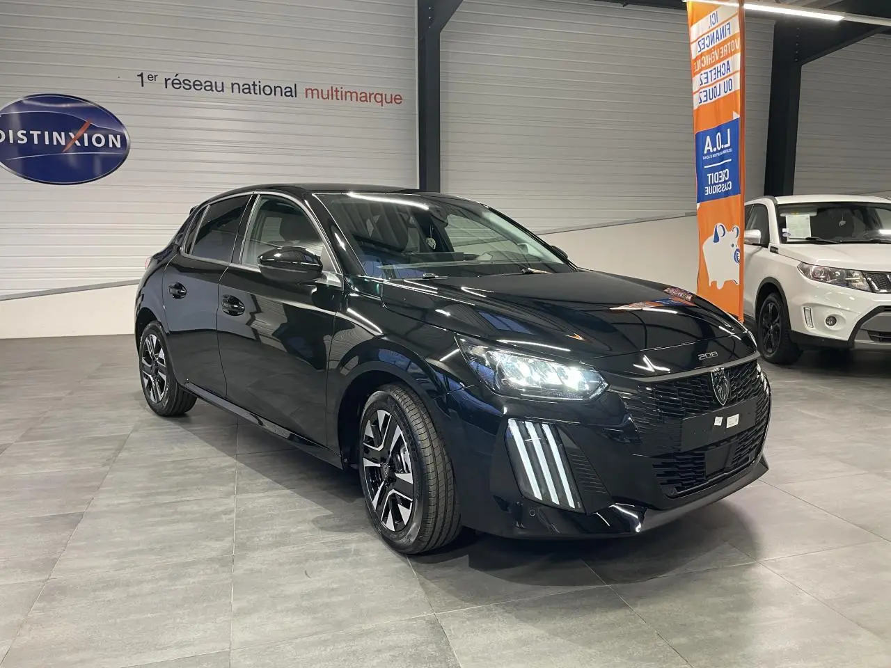 Peugeot 208 noir métallisé vue 3/4 avant droit, feux LED allumés et jantes alliage bi-tons visibles.