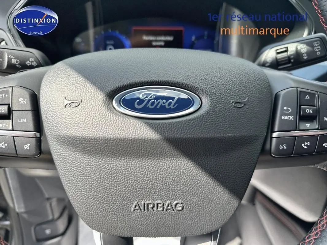 Gros plan sur le volant noir du Ford Kuga 2022 avec logo central et commandes intégrées de chaque côté.