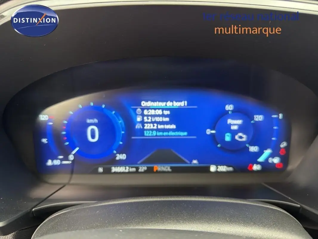 Vue rapprochée du tableau de bord numérique bleu du Ford Kuga gris foncé, affichant vitesse et informations de bord.