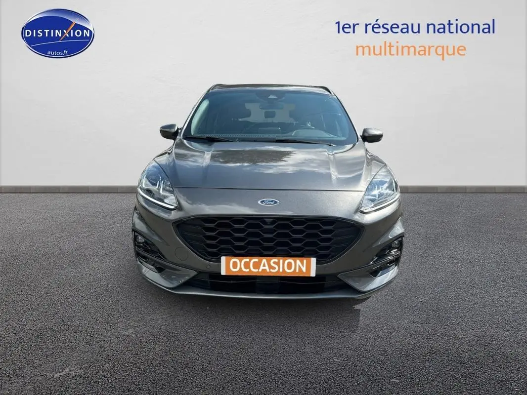 Vue avant d'un Ford Kuga gris foncé 2022 avec calandre noire et feux allumés sur fond neutre.