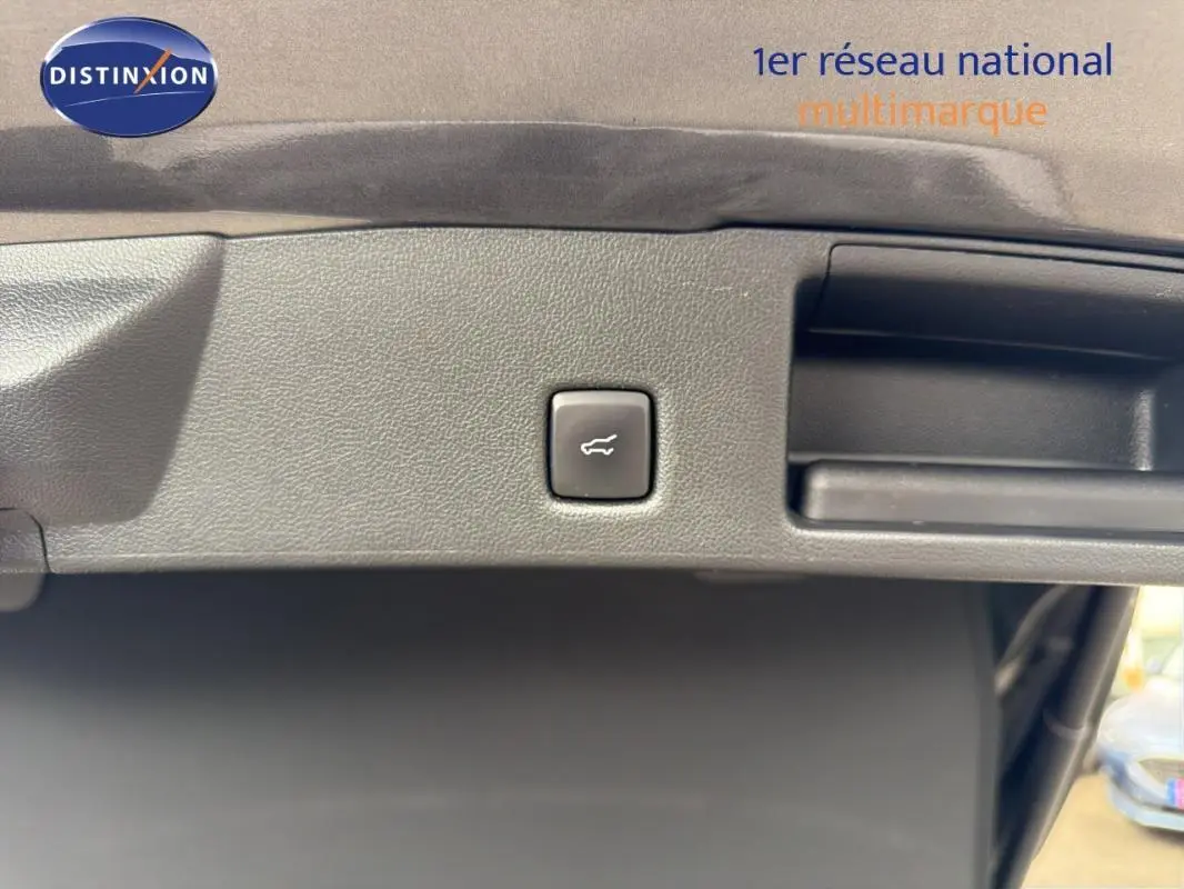 Bouton d'ouverture du coffre sur le hayon intérieur d'un Ford Kuga gris foncé, vue rapprochée.
