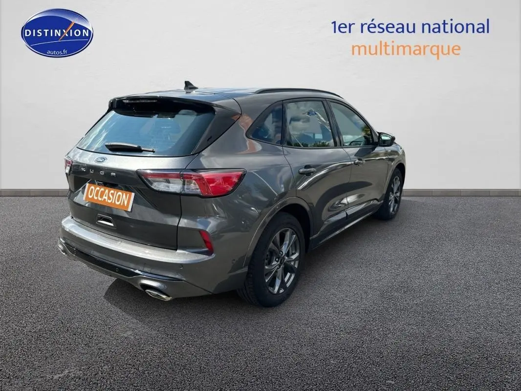 Vue 3/4 arrière droite d'un Ford Kuga gris foncé 2022 avec jantes alliage 18 pouces et attelage fixe visible.