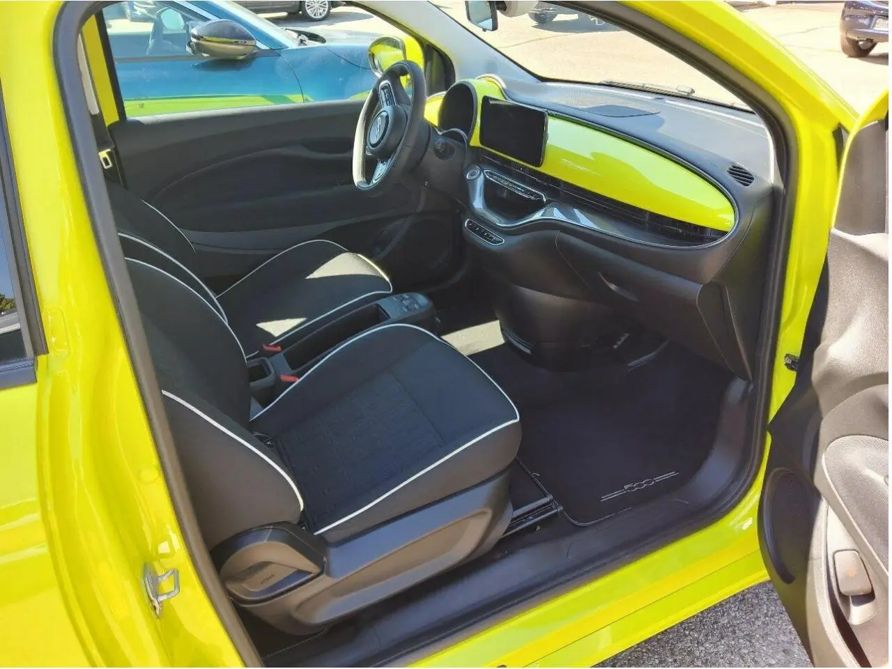 Intérieur de la FIAT 500 électrique jaune Acid vu côté conducteur, avec tableau de bord assorti et sièges noirs.