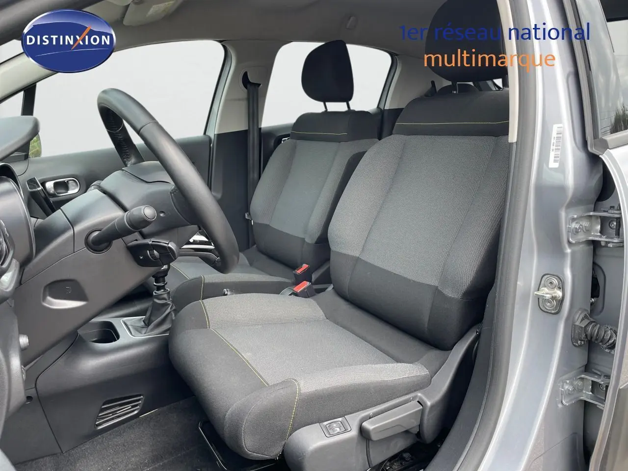 Vue intérieure côté conducteur de la Citroën C3 gris Artense 2021 avec sièges tissu gris et volant noir.