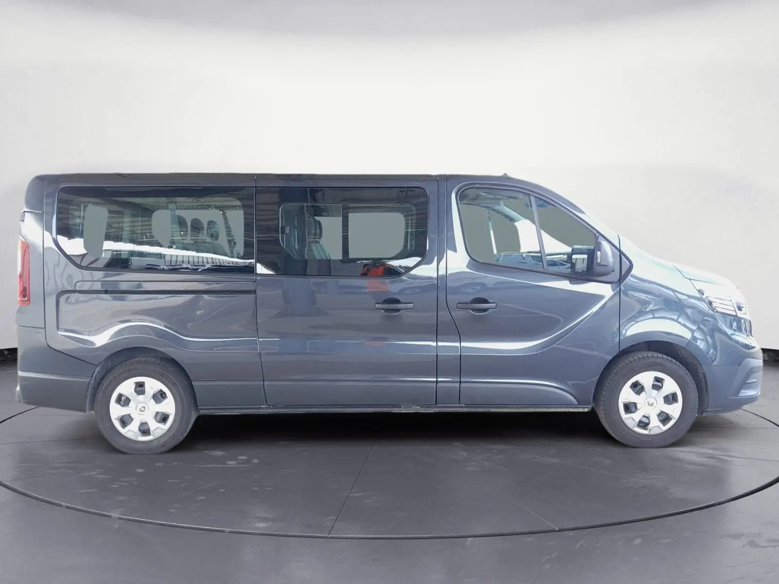Profil côté droit d'un Renault Trafic Combi gris foncé métallisé, version 9 places, avec vitres latérales teintées.