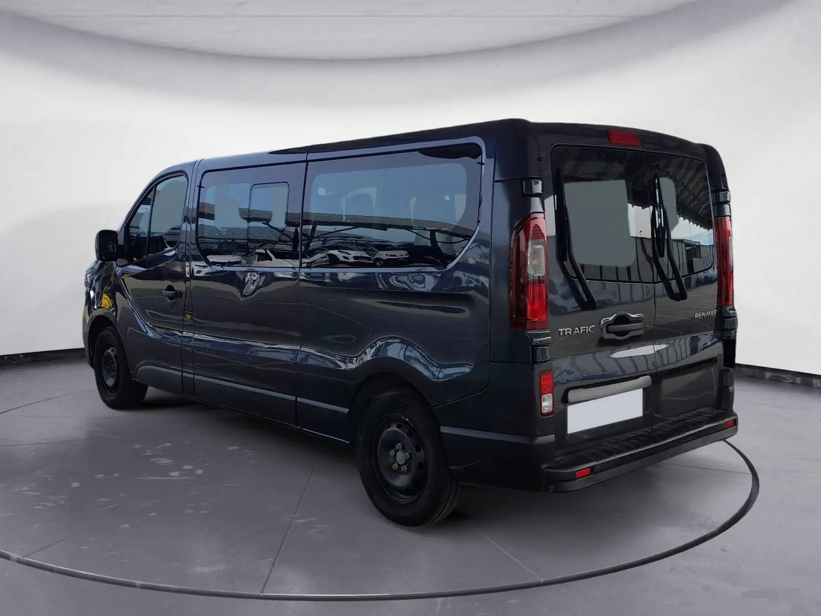 Vue 3/4 arrière droite du Renault Trafic Combi gris foncé métallisé, mettant en valeur ses grandes vitres latérales et ses feux arrière verticaux.