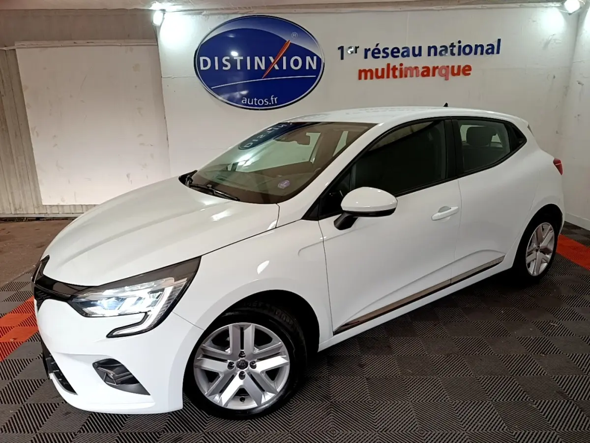 Renault Clio Business TCe 100 blanc vue 3/4 avant droit avec phares LED allumés en intérieur showroom