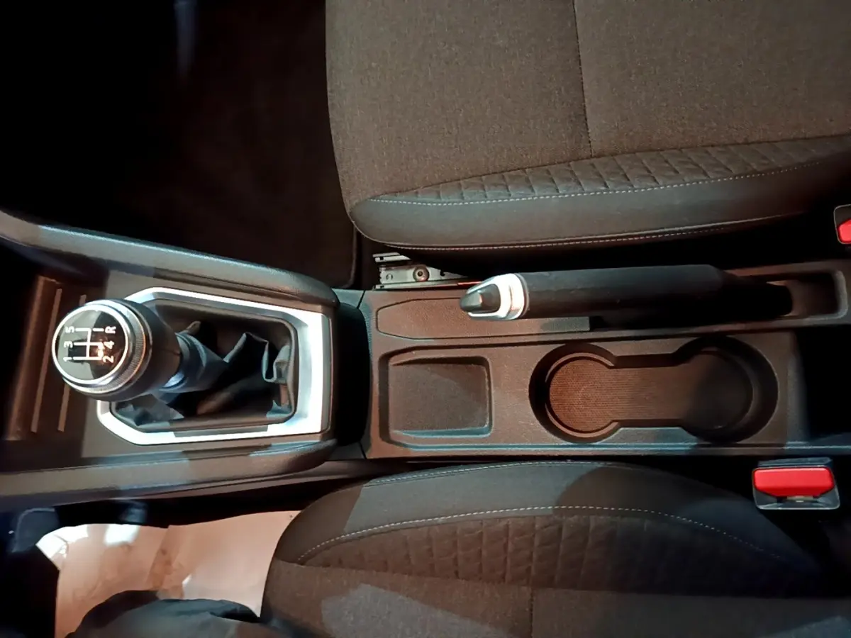 Vue plongeante sur la console centrale de la Renault Clio Business TCe 100, avec levier de vitesses manuel et frein à main entre sièges noirs.