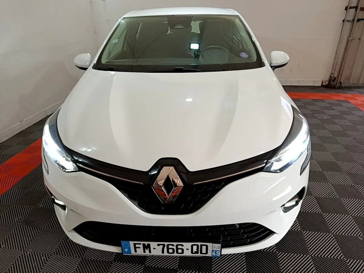 Vue frontale d'une Renault Clio Business TCe 100 blanche avec phares LED allumés et calandre noire brillante.
