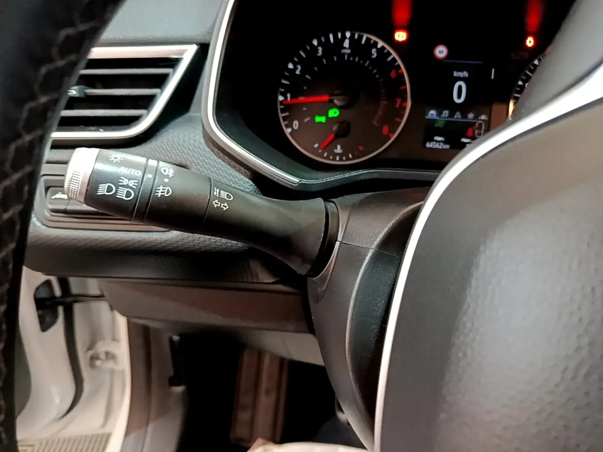 Gros plan sur le tableau de bord et la manette des phares d'une Renault Clio Business blanche de 2019.