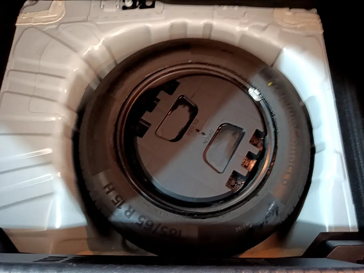 Roue de secours noire dans le coffre blanc d'une Renault Clio Business TCe 100 de 2019.